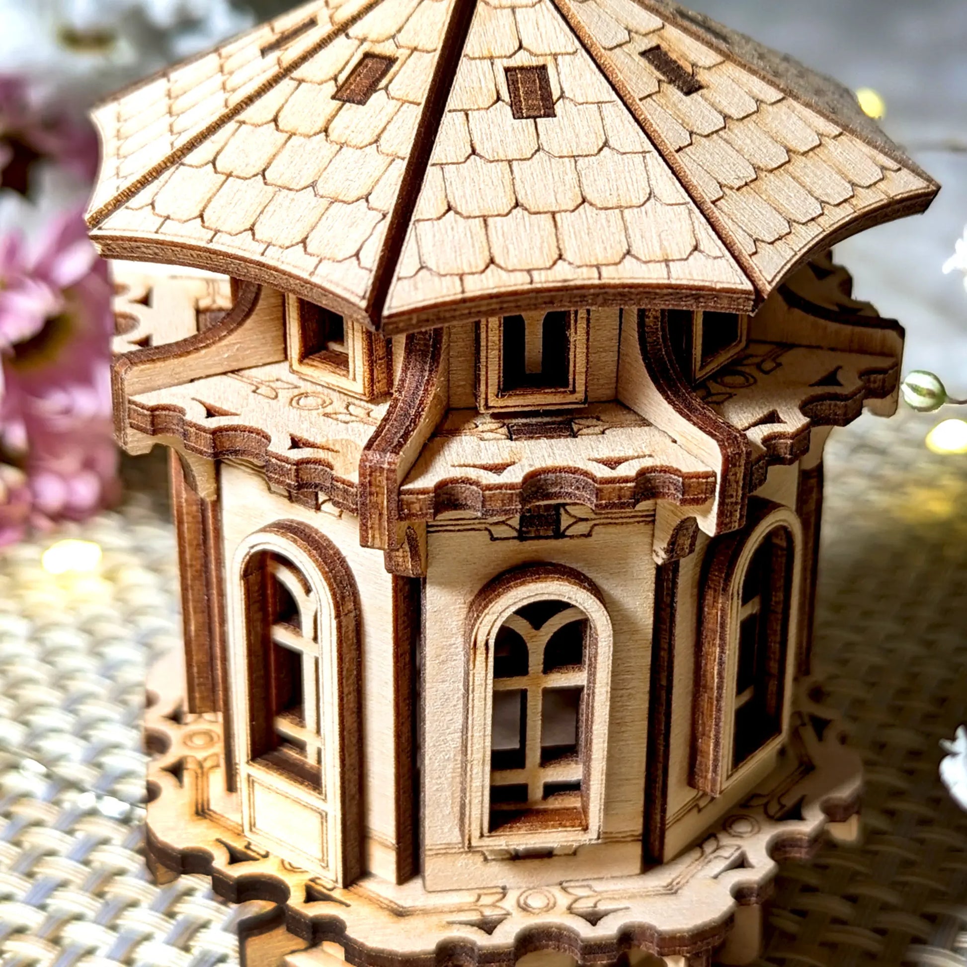 Close-up of a laser cut plywood tower, showcasing detailed engraved shingles and fine wood architectural features.