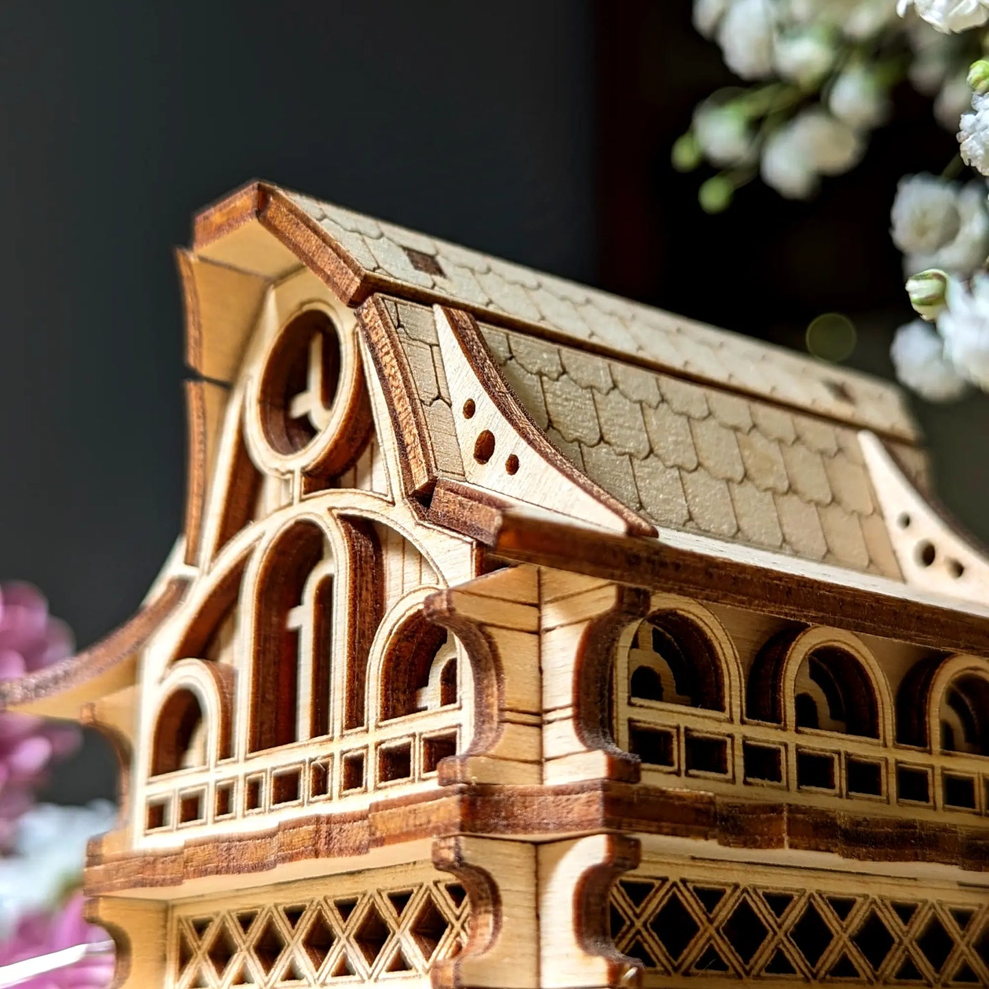 Macro shot of a laser cut plywood gnome house, highlighting precise wooden engravings and fine architectural craftsmanship.