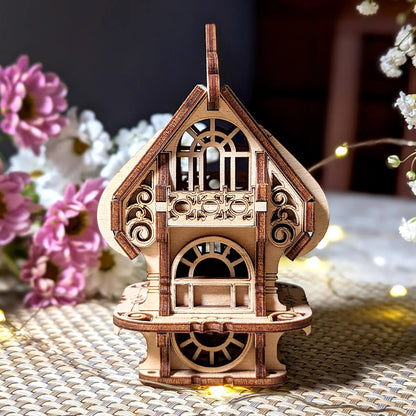 Front view of laser cut plywood miniature house featuring ornate arched windows, small balcony, and wood details.