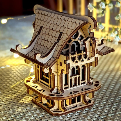 Side view of a laser cut plywood fairy house with hanging lantern, staged with soft flowers and warm lights.