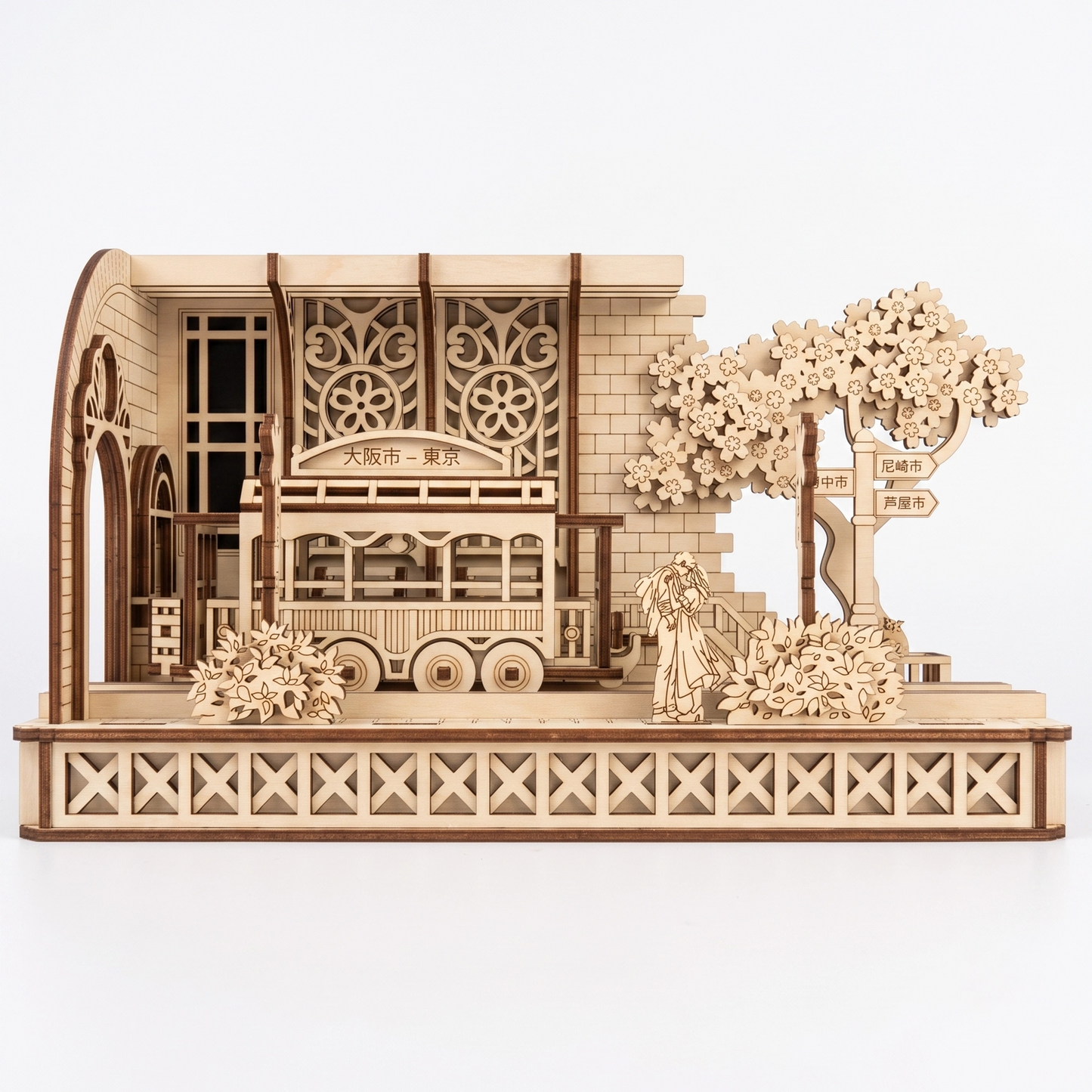 Front view of a laser-cut birch plywood Japanese tram station model with a tram, cherry tree, and dark burnt edges