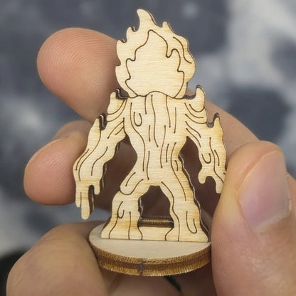Back view of a laser cut plywood lava elemental figurine held by hand. Shows vertical wood grain and dripping magma drips