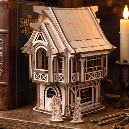 Medieval village house made of laser cut plywood displayed on a bookshelf next to fantasy novels
