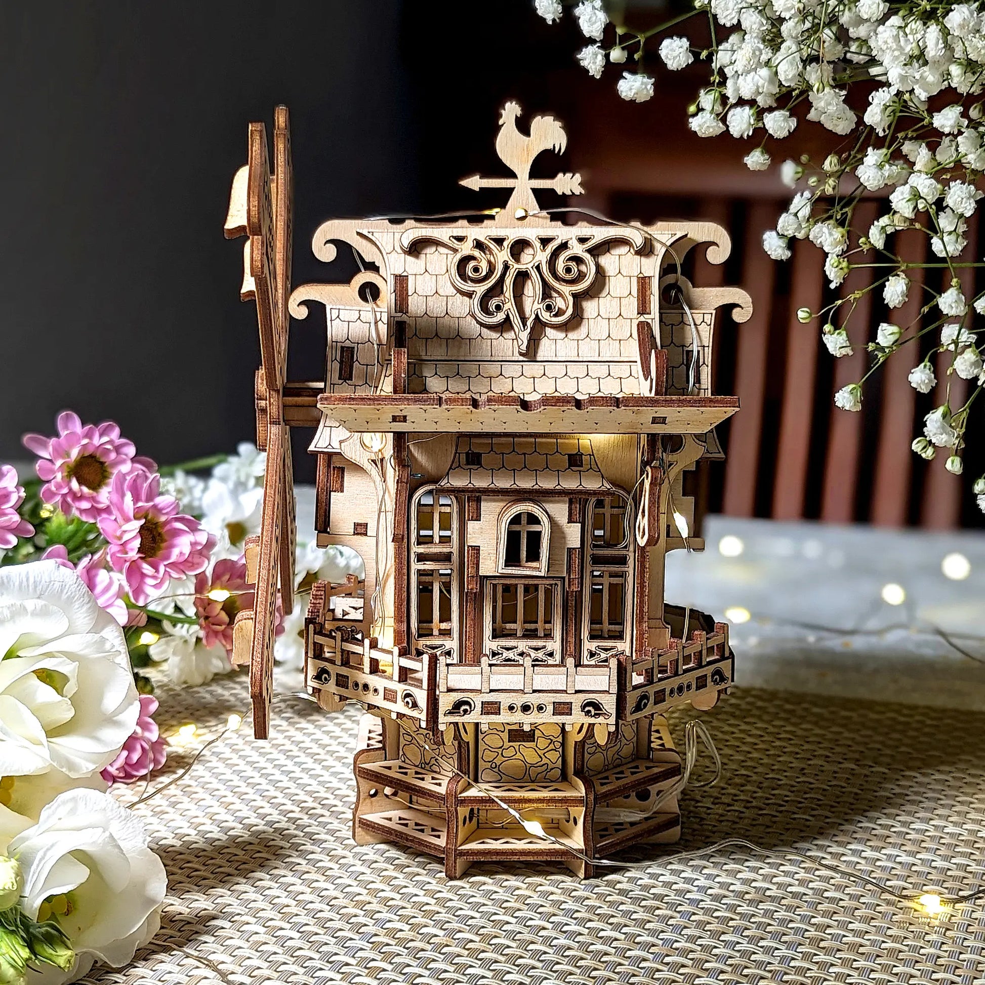 A lovely straight side profile of an intricate 3D holiday windmill with warm lighting, beautifully made of laser cut plywood.