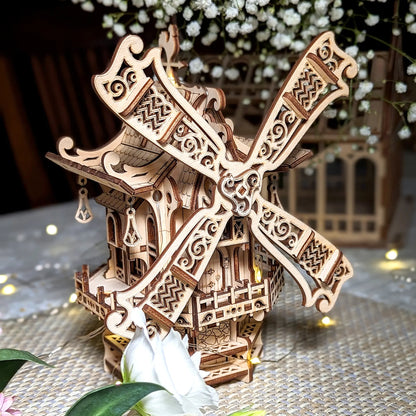 Elegant front shot of a decorative 3D windmill with ornate filigree sails, crafted from glowing laser cut plywood layers.