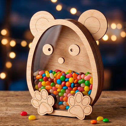 Laser cut plywood bear shaped candy box with a clear acrylic window filled with jelly beans on a blurry bokeh background.