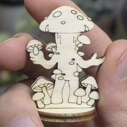 Back view of a laser cut plywood mushroom folk held in hand. Highlights the dark burnt edges and natural wood grain texture