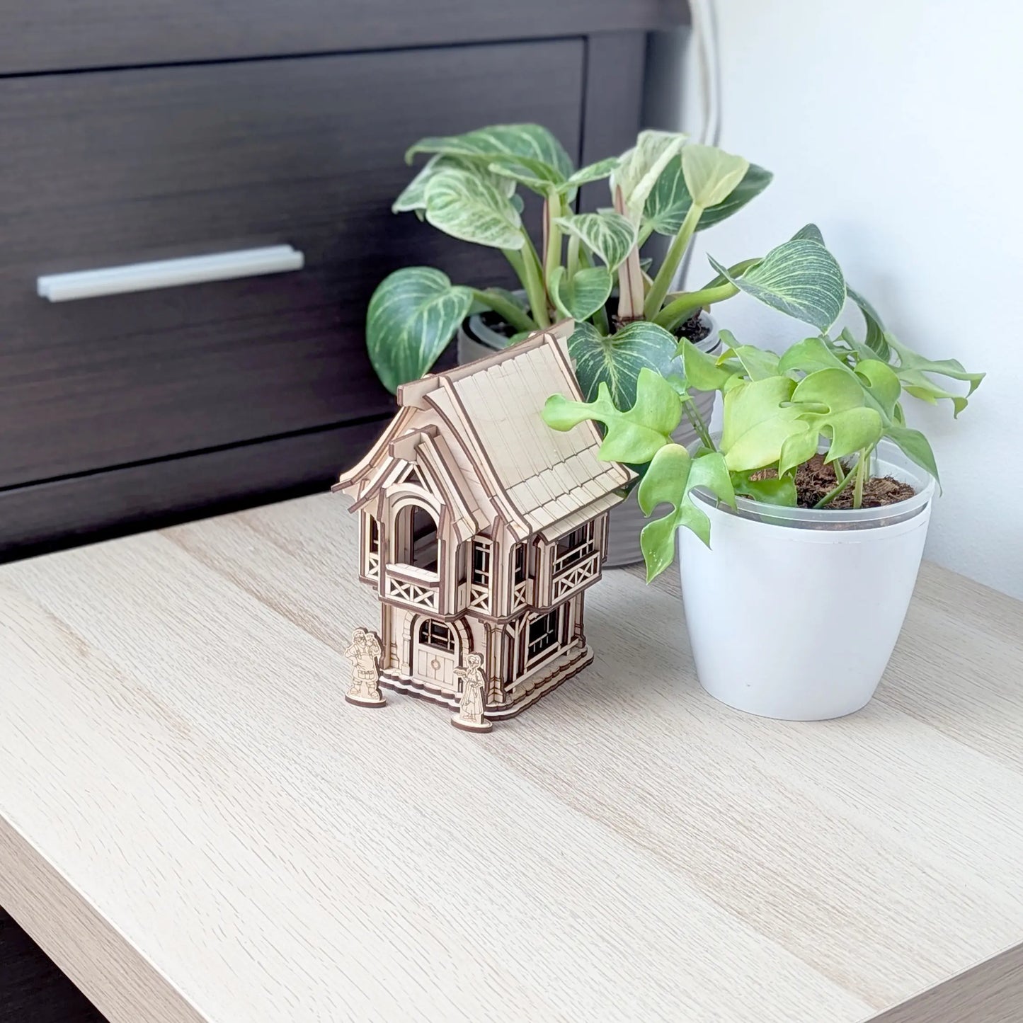 Detailed close-up view of stone brick textures and tiny window frames on a gabled wall of a laser cut plywood model house.