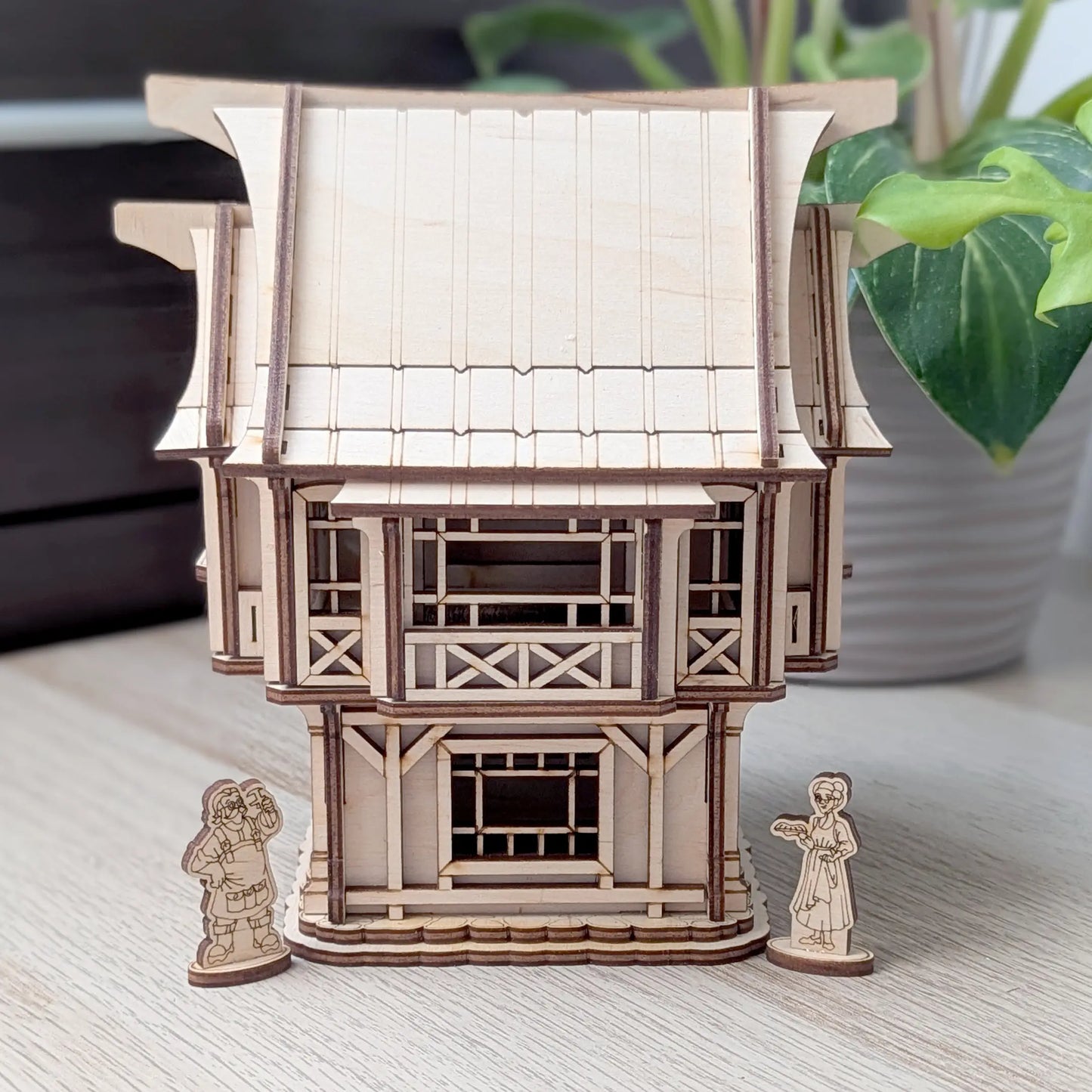 A crisp high angle shot showing a detachable roof panel resting next to an open internal layout of a laser cut plywood house.