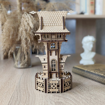 Miniature fairy castle tower made of laser cut plywood stands on a wooden desk next to a white bust decor.