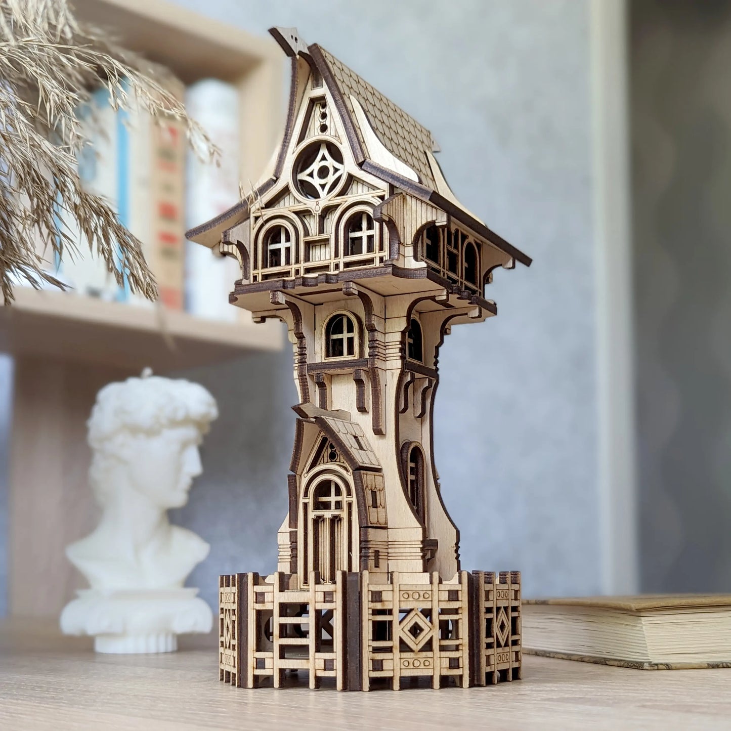 Close up of a detailed fantasy tower model of laser cut plywood showcasing layered windows and wood grain.