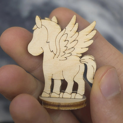 Profile of a laser cut plywood Pegasus held in hand. Highlights the dark burnt edges and delicate wing feather carvings