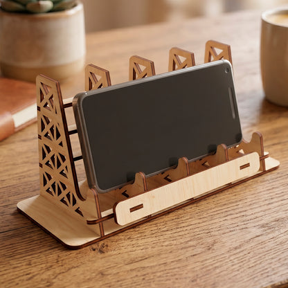 Laser cut plywood multi slot phone holder stand with a smartphone, featuring geometric truss design on a wooden table.