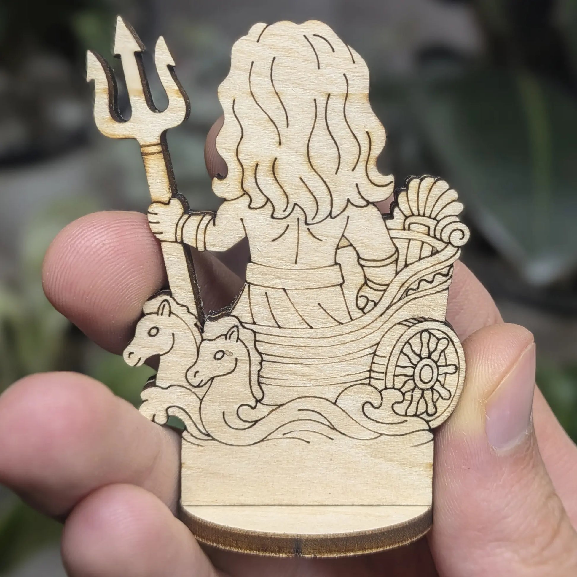 Back view of a laser cut plywood Poseidon held in hand. Highlights the dark burnt edges and natural wood grain texture
