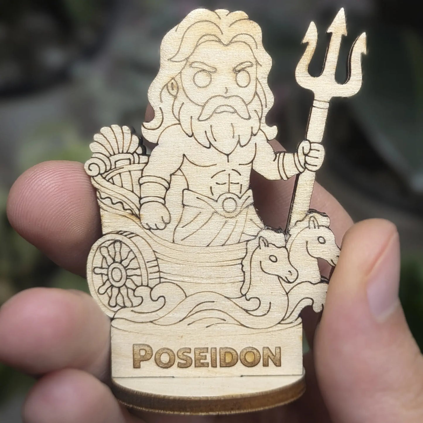 Hand holds a laser cut plywood Poseidon for scale. Shows the detailed trident, crown, and flowing beard at tiny scale