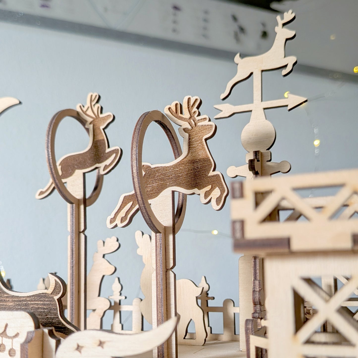 Cut wooden reindeer figures positioned on tall stands and hoops in a festive scene made from a laser cut digital file, with layered silhouettes and holiday accents