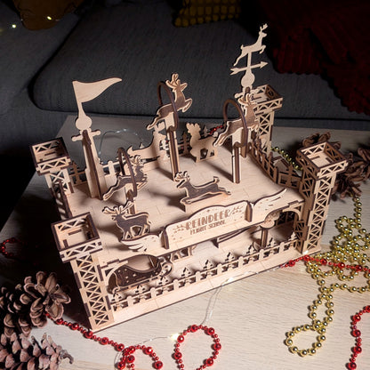 Top angled view of the assembled wooden “Reindeer Flight School” model made from a laser cut digital file, showing multiple reindeer figures, platforms, and sleigh details.