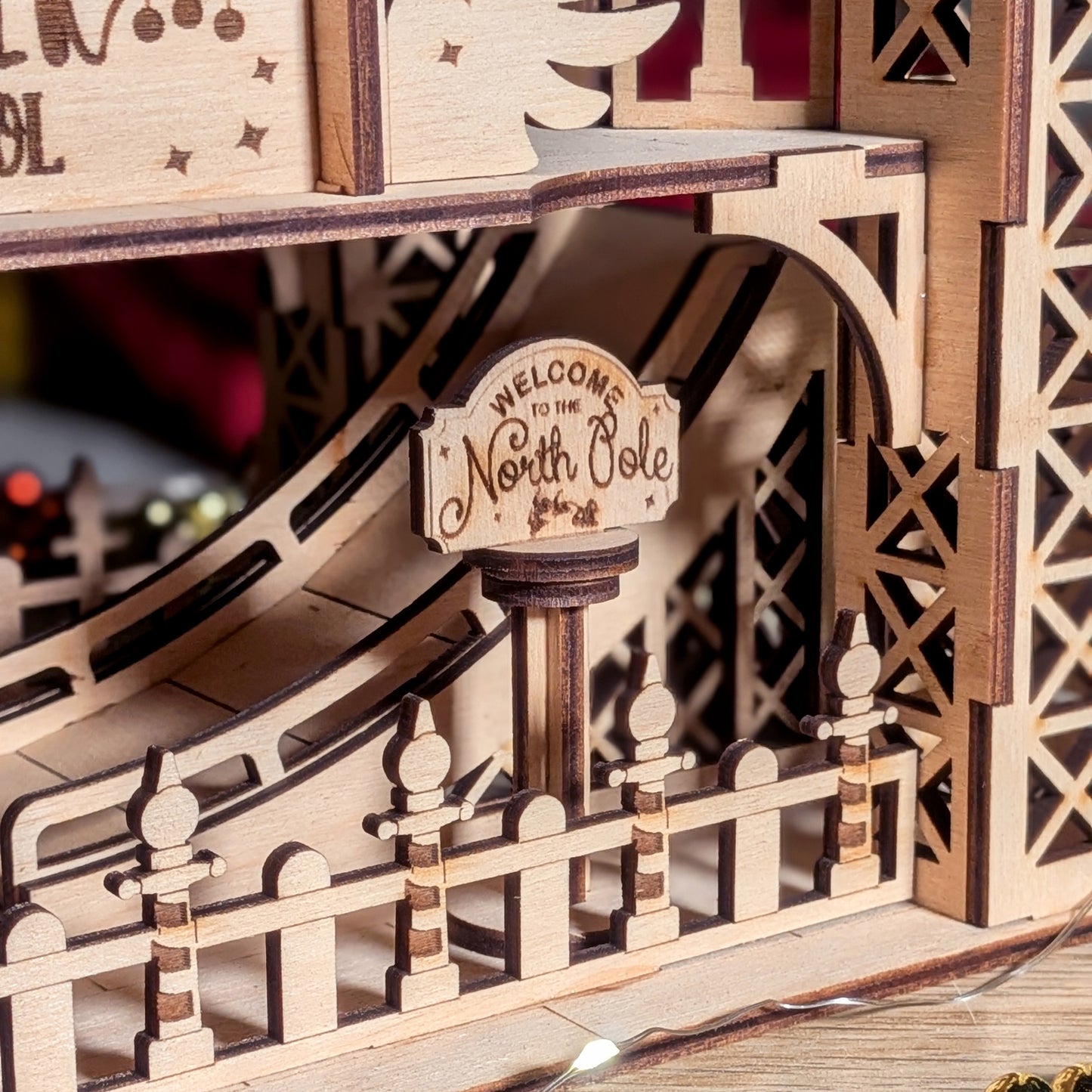 Close-up of the engraved “Welcome to the North Pole” sign in a wooden Christmas display made from a laser cut digital file, with layered fence and curved ramp details.