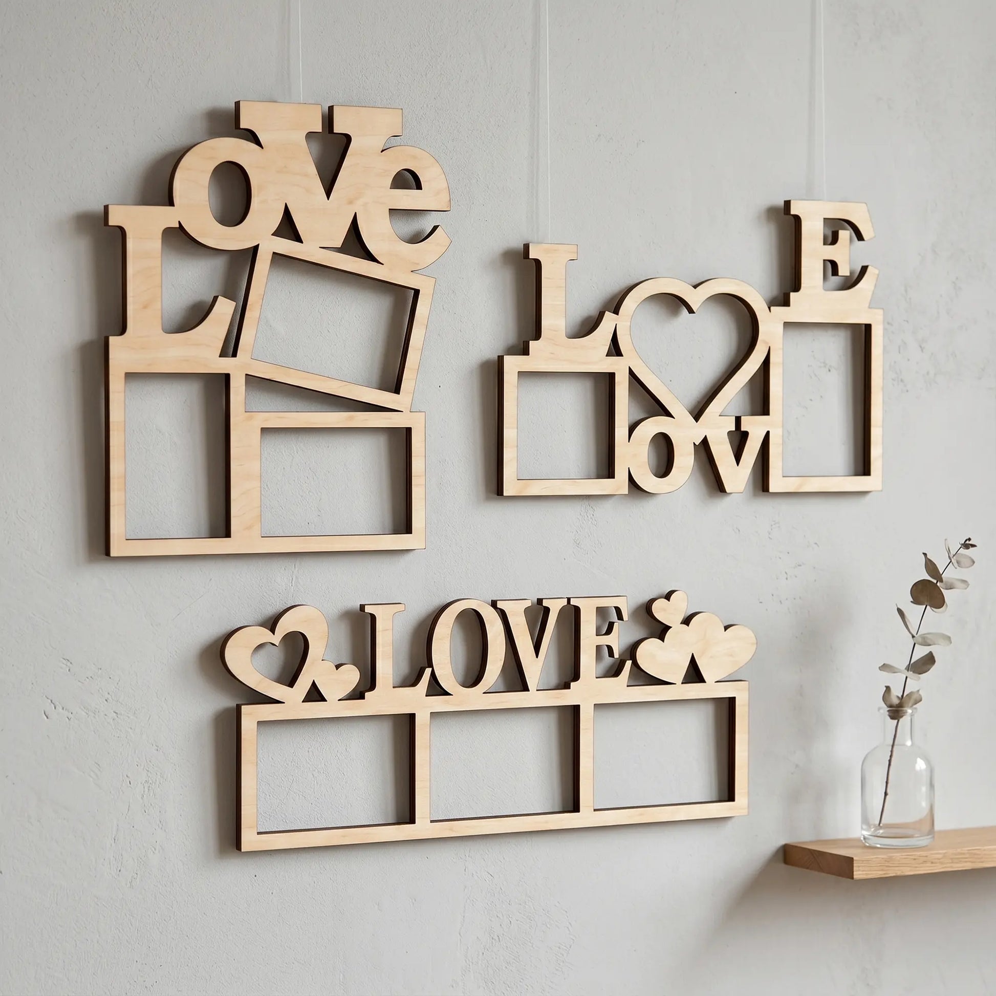 Set of three empty laser cut plywood wall frames with LOVE and heart designs hanging on a light textured minimalist wall