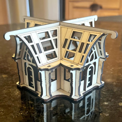 Miniature laser cut plywood greenhouse lantern centerpiece standing on a glossy dark kitchen counter, home staging.