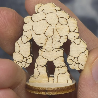Back view of a laser cut plywood stone golem held in hand. Shows dark burnt edges and jagged rocky segments of the figure