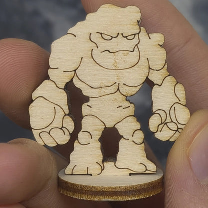 Hand holds a laser cut plywood stone golem for scale. Front view shows jagged rock segments and engraved facial features