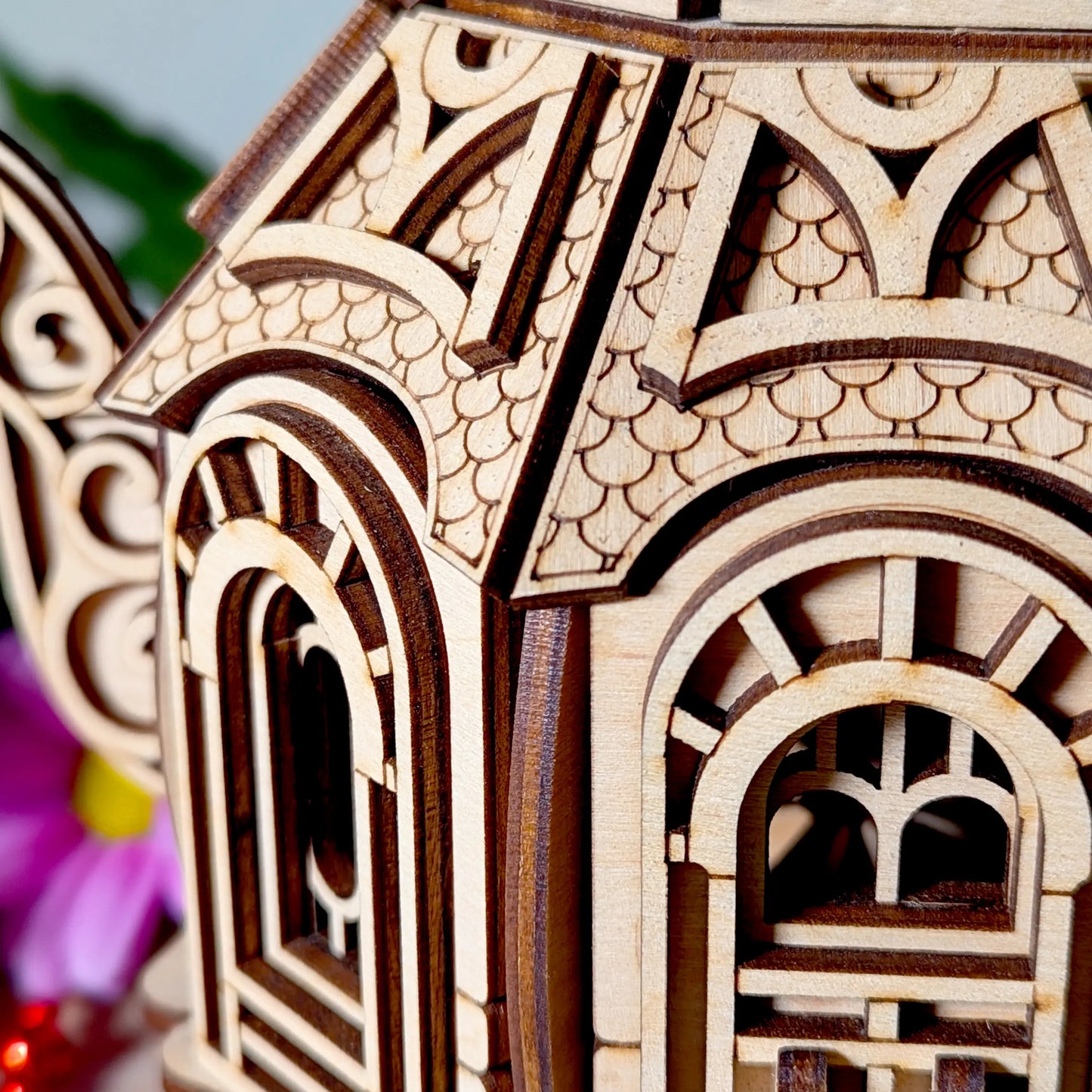 Macro view of engraved scale patterns and clean burned edges on a decorative laser cut plywood teapot model.