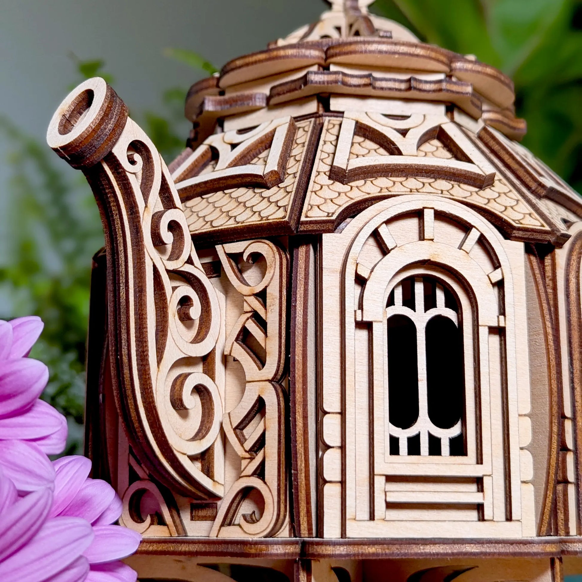 Close-up of a decorative swirl spout and detailed window panel on a miniature laser cut plywood teapot house.
