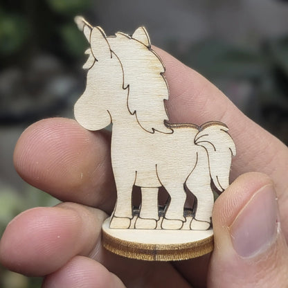 Back view of a laser cut plywood unicorn held in hand. Highlights the dark burnt edges and layered mane and tail engravings