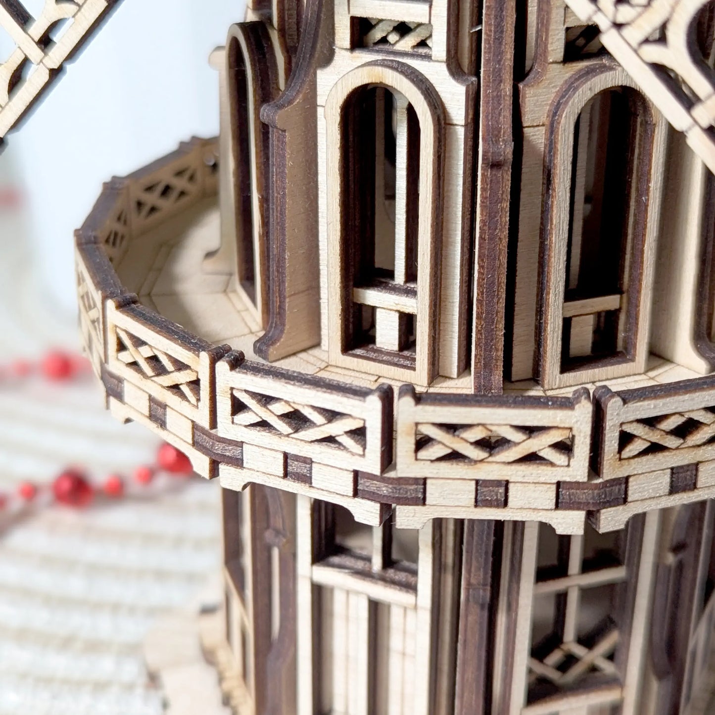 Macro close-up view focusing on the intricately patterned wrap-around balcony railing of the laser cut plywood model.