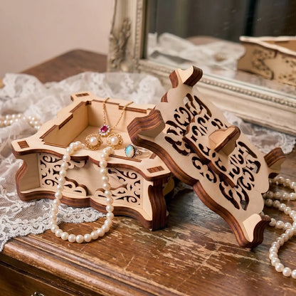 Laser cut plywood filigree jewelry box with pearl necklace and rings on lace near a vintage mirror background.