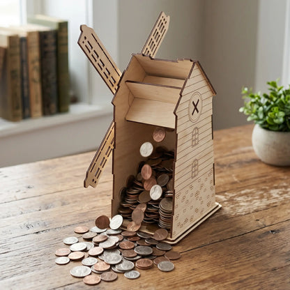 Laser cut plywood windmill money box opened at the back, pouring a large pile of coins onto a rustic wooden table.