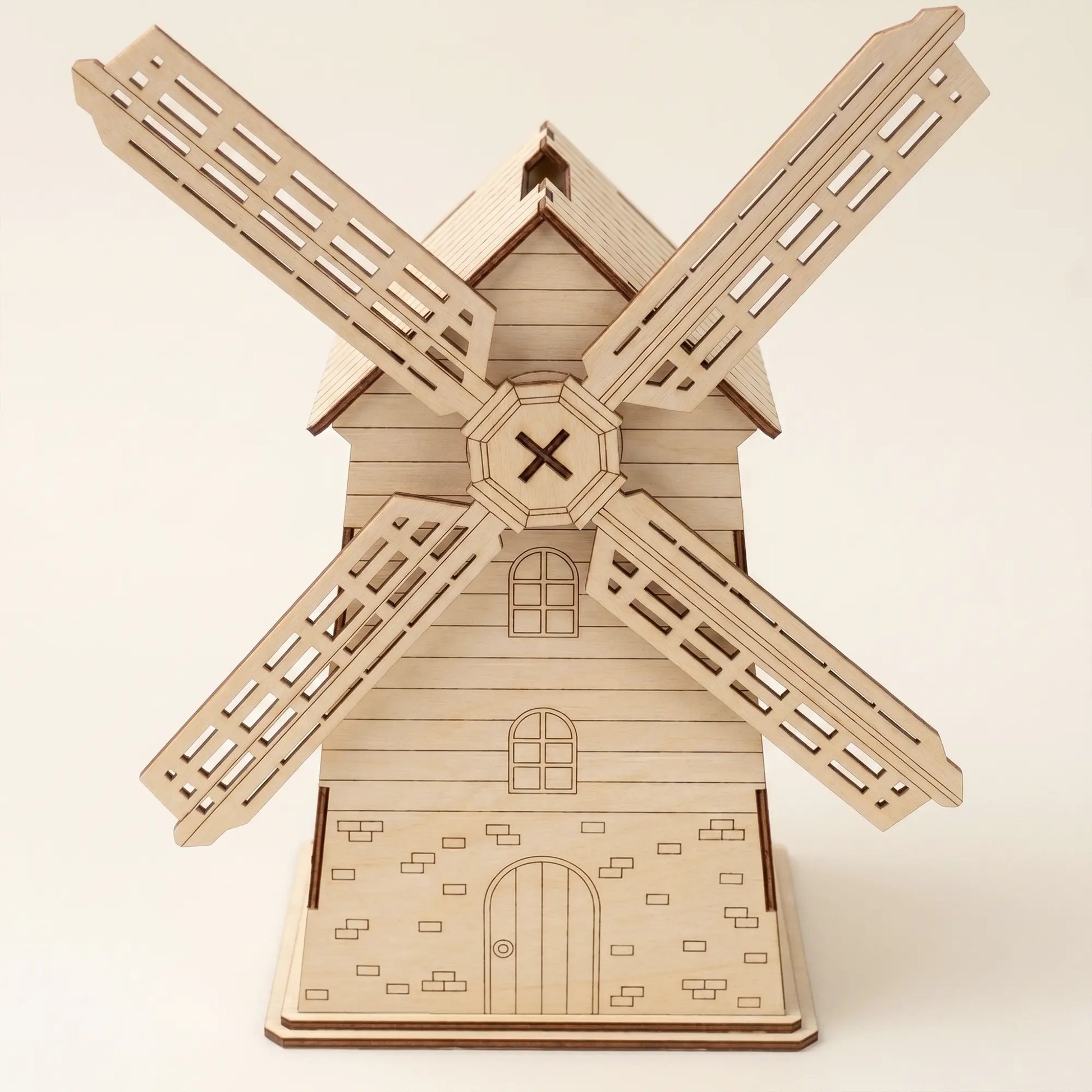 Front view of a laser cut plywood windmill money box with detailed windows, engraved door, and brick pattern base.