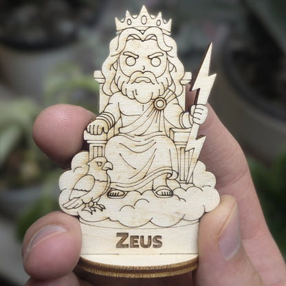 Hand holds a laser cut plywood Zeus for scale. Front view showing lightning bolt, laurel crown, and detailed beard engraving