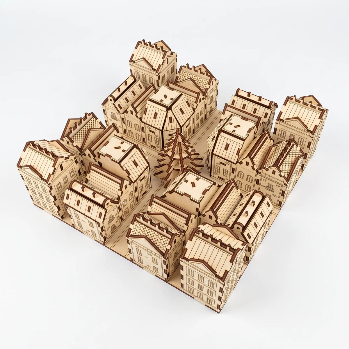 High angle view of laser cut plywood advent calendar city model with tiny houses and central fir tree on white background.