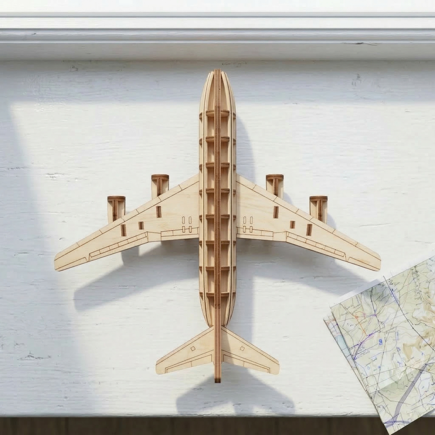 Wooden laser cut airplane model on a white surface with a map