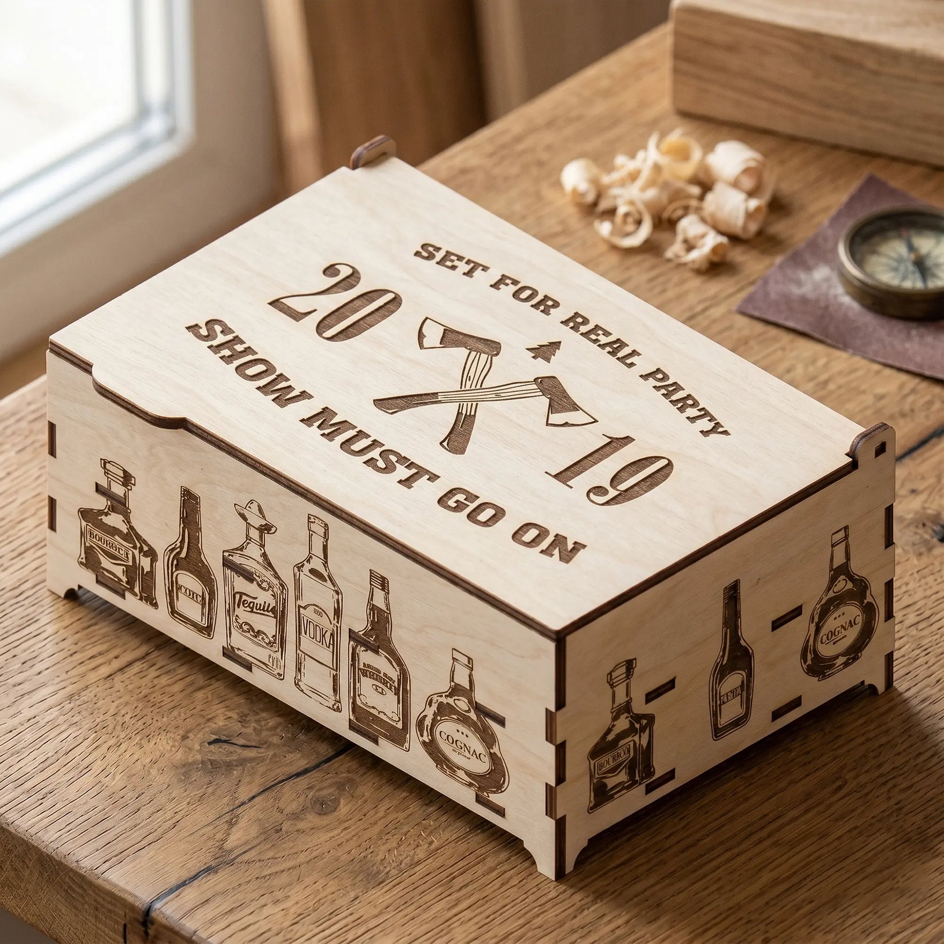 Custom laser cut plywood gift box engraved with 'Set for Real Party' and bottle illustrations on a rustic wooden table