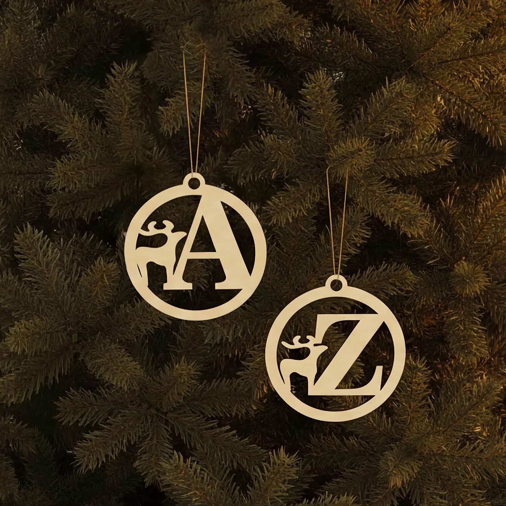 Personalized laser cut Alphabet for Christmas tree in elegant circle frames with integrated deer motifs and hanging loops, set against a festive lighted Christmas tree background.
