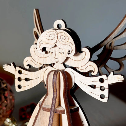 Wooden laser cut angel ornament with outstretched wings on a dark background