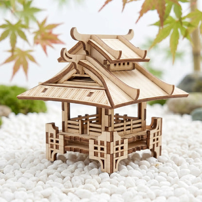 Wooden model of a traditional Japanese pagoda on pebbles with blurred leaves in the background