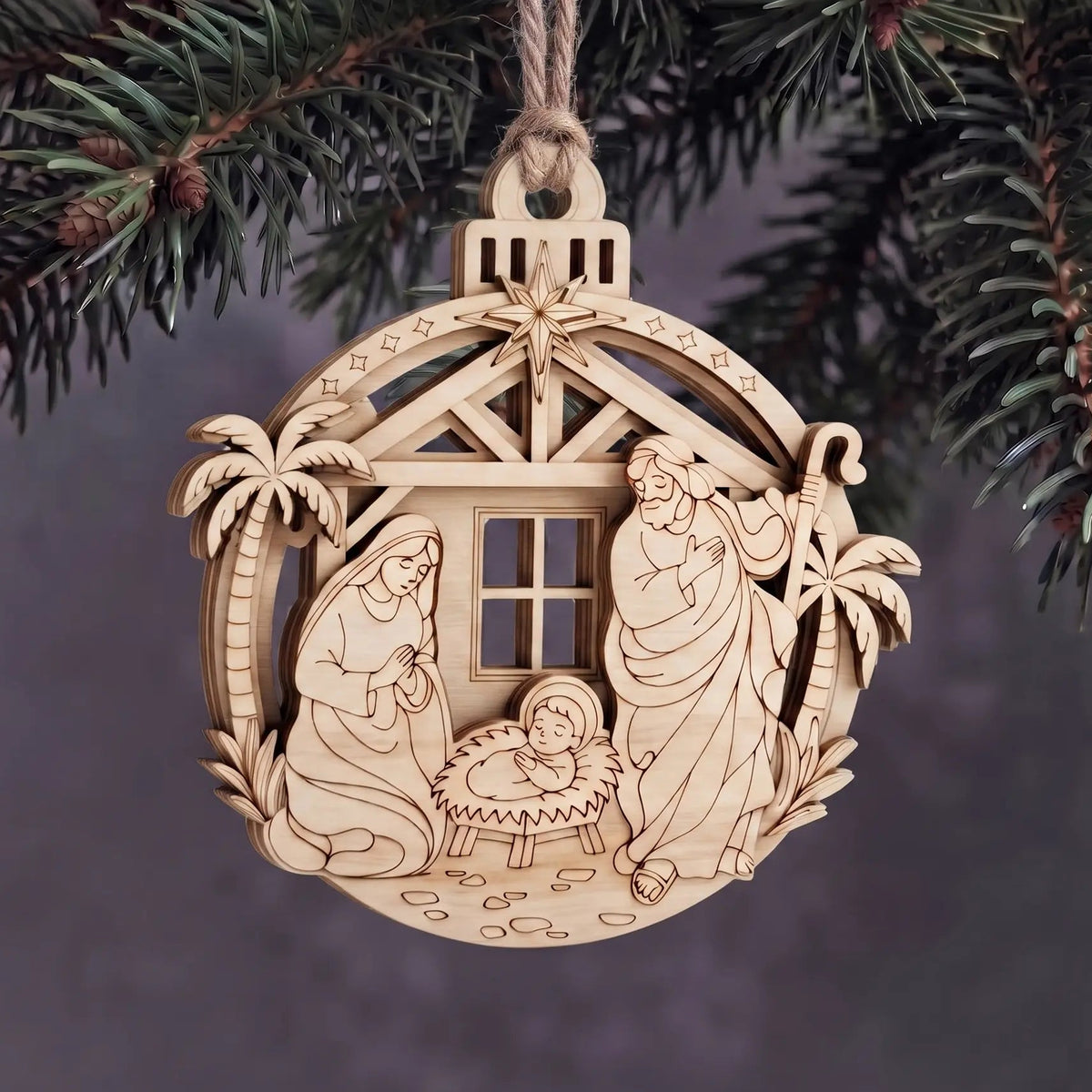 Layered laser cut plywood Holy Family nativity ornament hanging with twine rope on evergreen Christmas tree boughs
