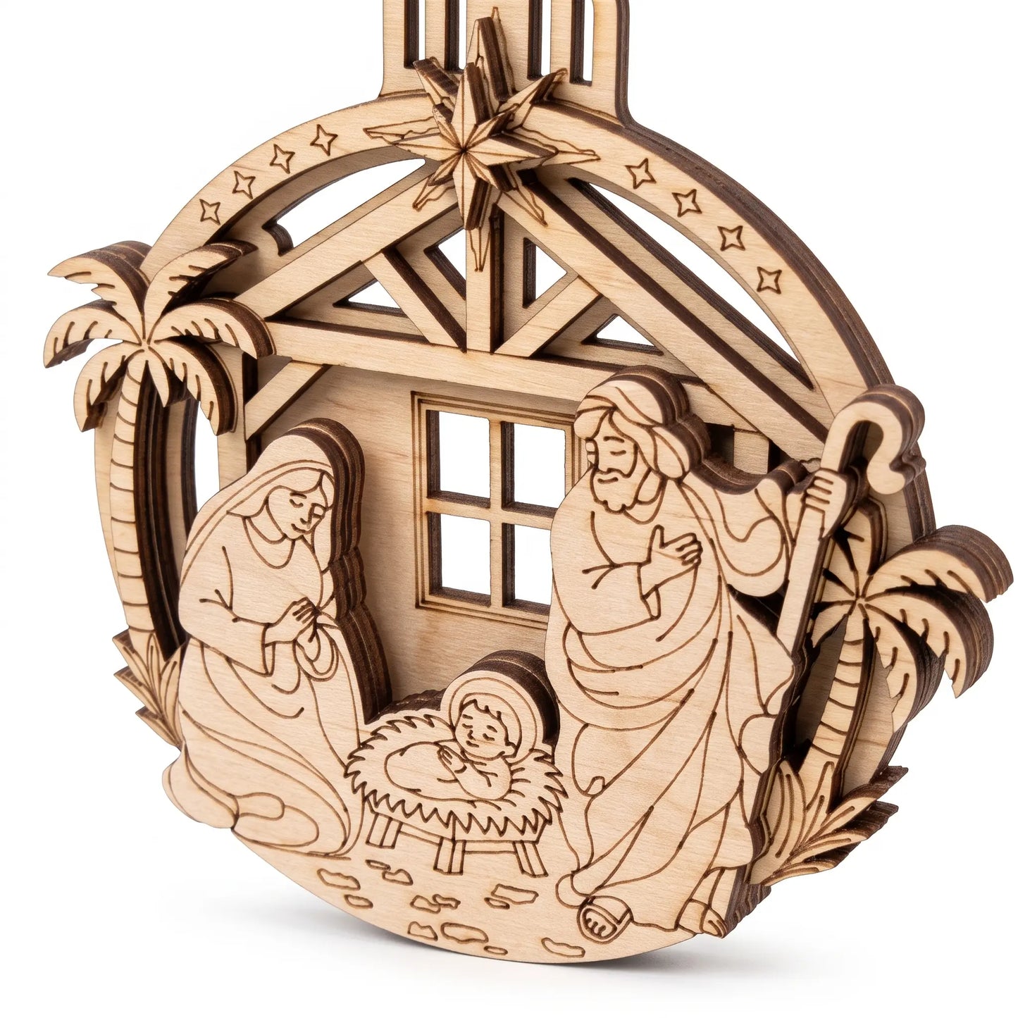Angled close-up of multilayered laser cut plywood nativity bauble showing clean 3D relief edges on white background