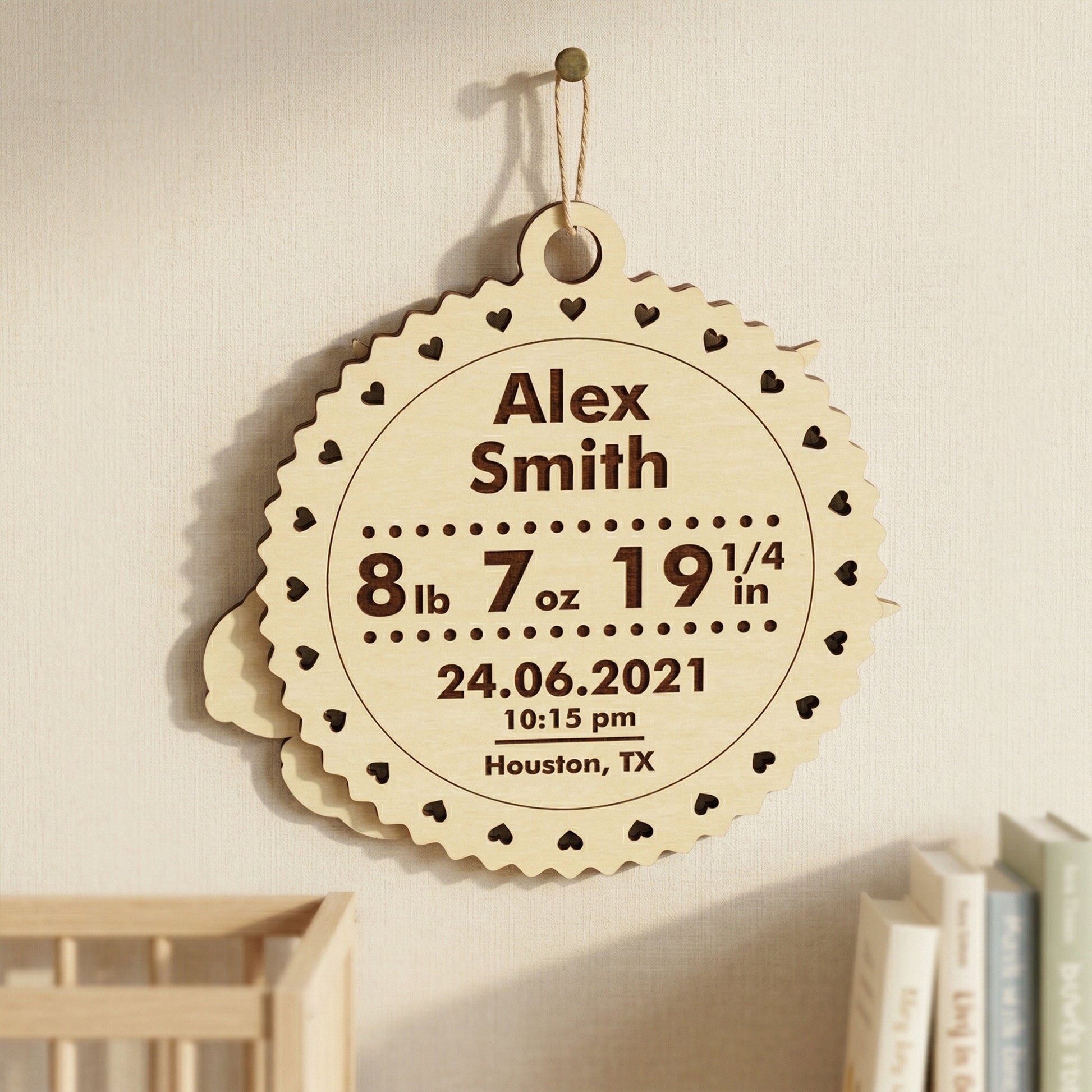 The back of a personalized laser-cut wooden baby plaque, showcasing engraved birth statistics. Includes the name "Alex Smith," weight, length, date, time, and city (Houston, TX). The light wood ornament features a decorative heart-scalloped edge and hangs in a modern nursery setting.