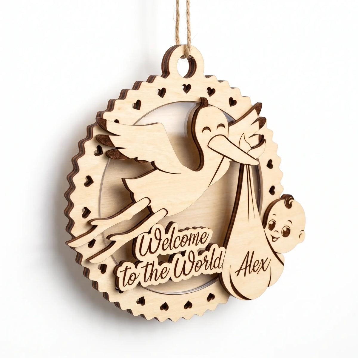 3D layered laser cut plywood baby birth plaque ornament with stork holding newborn baby in bundle on plain white background.