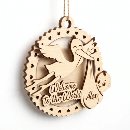 3D layered laser cut plywood baby birth plaque ornament with stork holding newborn baby in bundle on plain white background.