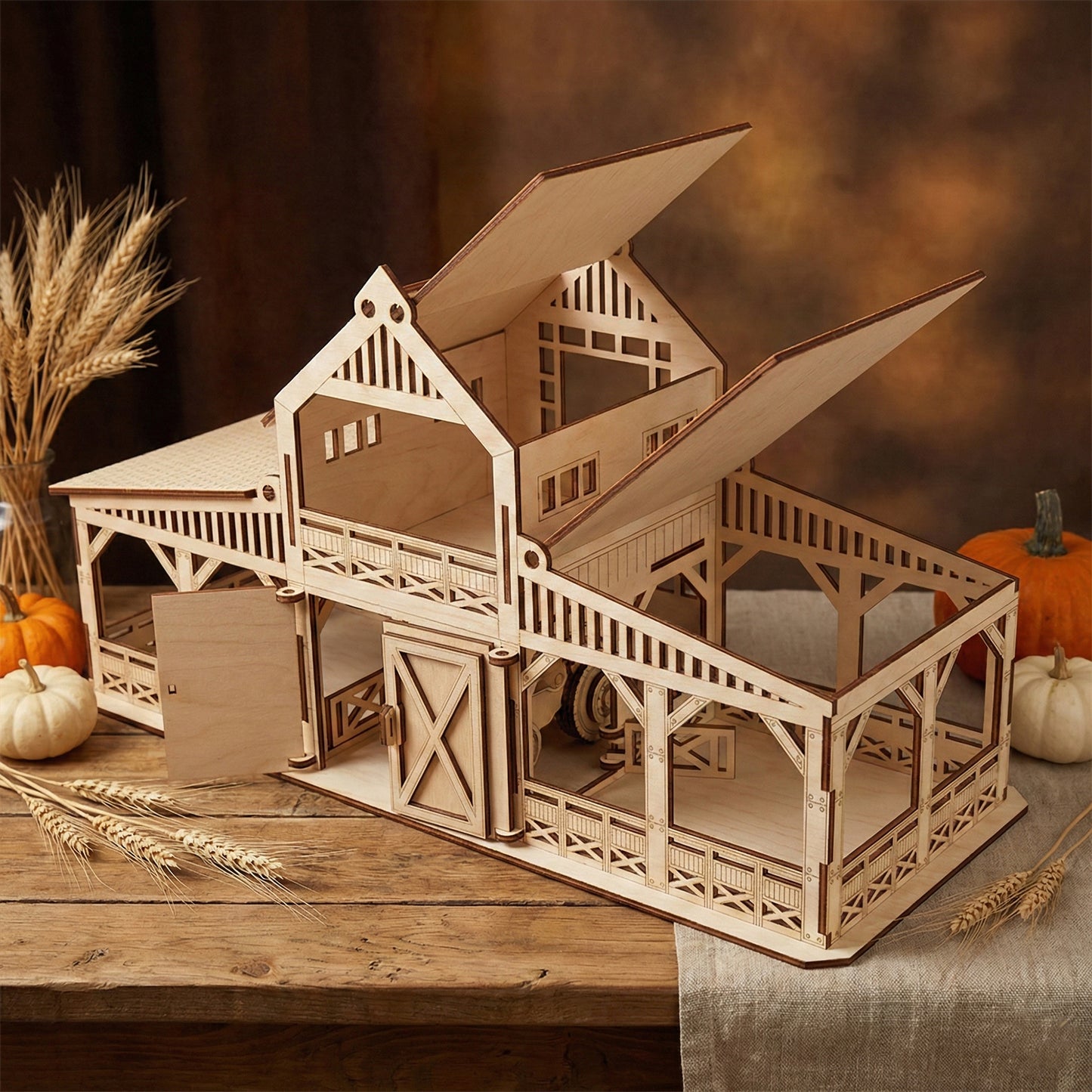 Side perspective of the laser cut plywood barn showing the hinged roof panels flipped open to reveal the interior loft. Detailed support columns and cross-hatch railings are visible against a warm, rustic background.