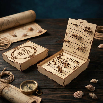 A wooden Battleship game made of laser cut plywood, open on a dark desk. Features two 10x10 grids with miniature ships and pins. Nautical styling with a brass compass, old map, and rope. The lid is engraved with "Battle Ship" inside a target.