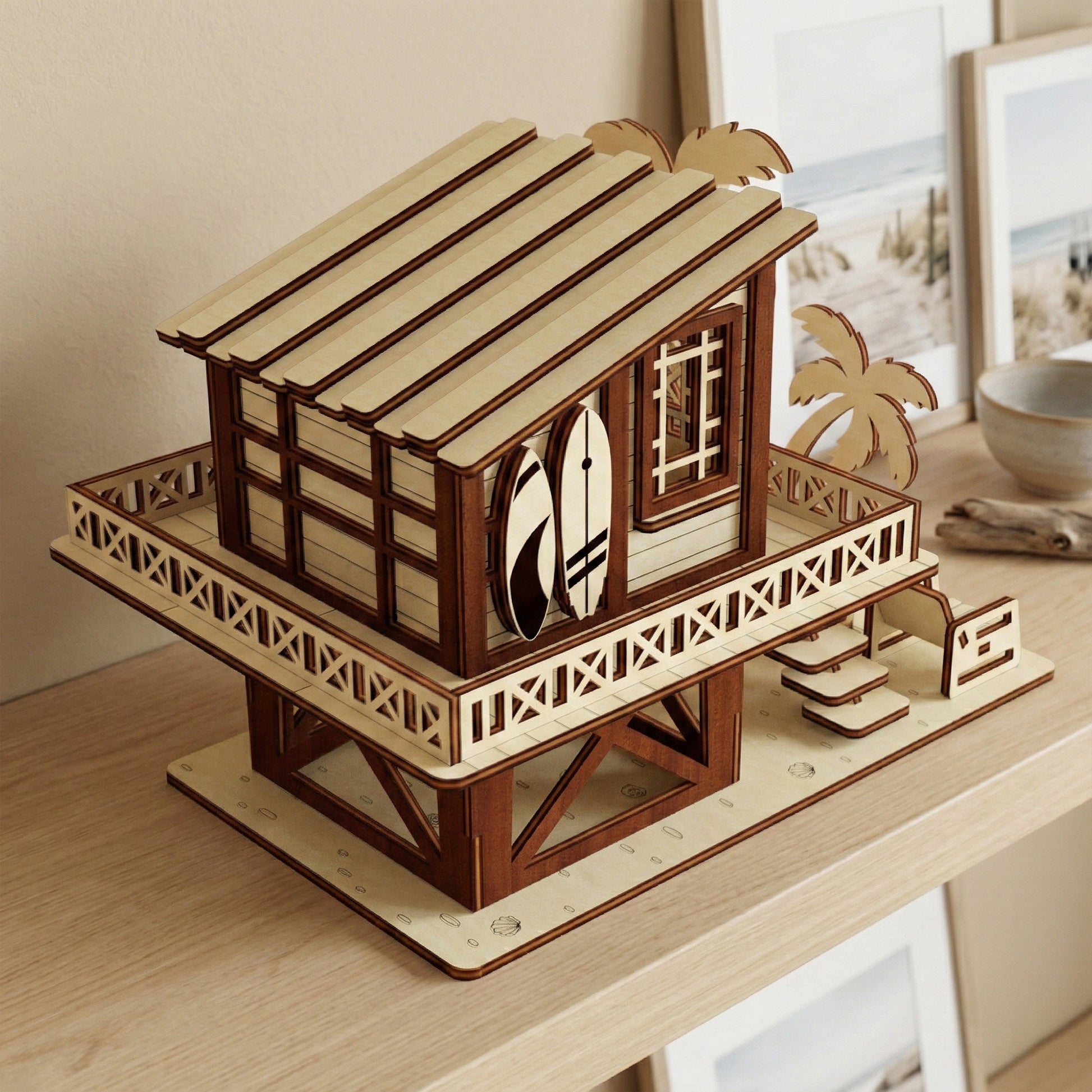 Detailed close-up of the laser cut plywood beach house entrance. Features include a tiny wooden table and chair, a large palm tree silhouette, and seashells scattered on the surrounding wooden surface.