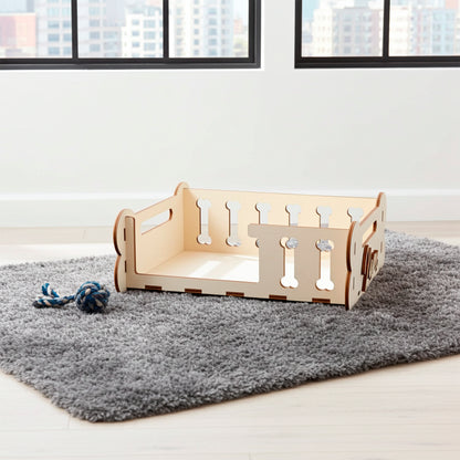 Laser cut plywood wooden Dog Bed frame or storage box with decorative side panels featuring bone-shaped cutouts and personalized engraved text ("Maxie"). The light wood bed, designed as a DIY kit, is displayed on a textured gray rug next to a toy, showing its capacity and function as a pet accessory in a modern interior setting.