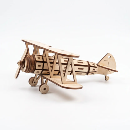 A wooden laser cut model of a biplane, with a propeller and two sets of wings, is shown against a white background.